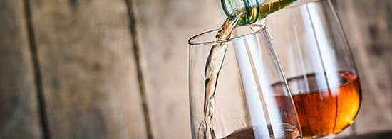 Flasche füllt Weißwein in Glas