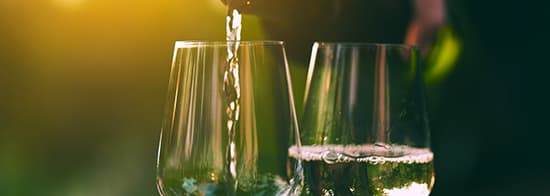Weinflasche füllt Weißwein in Glas