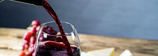 Weinglas indem gerade Rotwein eingeschüttet wird