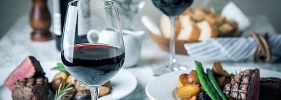 Gedeckter Tisch mit Merlot und Fleischgericht