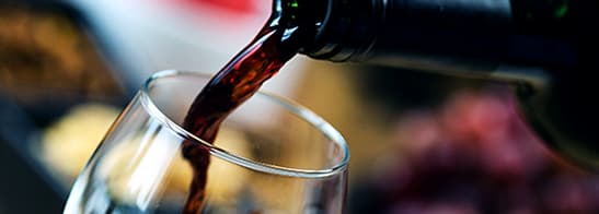 Rotwein fließt aus Flasche in Glas