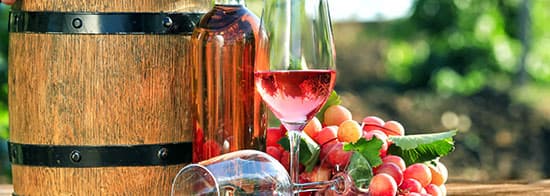 Spanischer Roséwein mitkleinem Fässchen und Trauben im Hintergrund