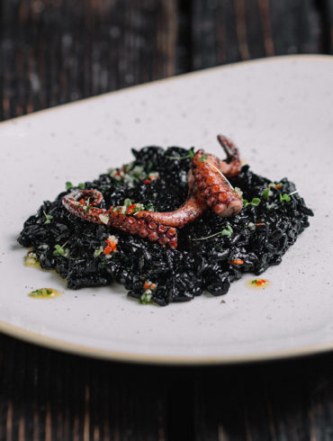 Schwarzes Risotto mit Tintenfisch ist ein extravaganter Klassiker der Küche Venetiens. Wir zeigen Ihnen, wie Sie Ihre Gäste erstaunen und geben Weinempfehlungen.