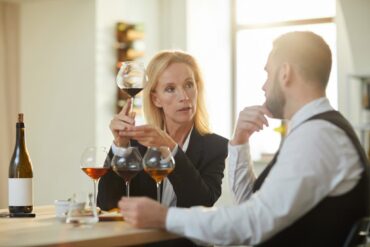 Mann und Frau sitzen an Tisch und tauschen sich über Wein aus