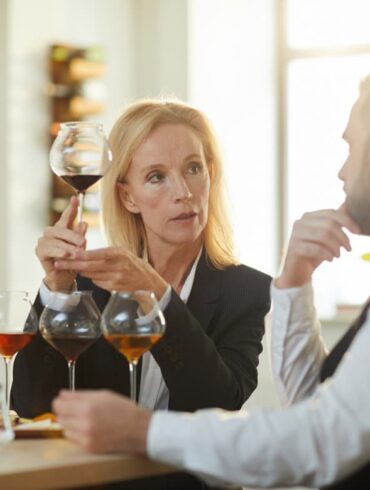 Mann und Frau sitzen an Tisch und tauschen sich über Wein aus