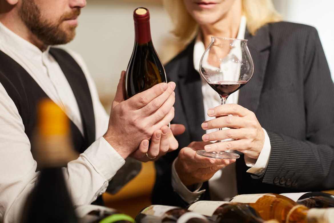 Mann hält Weinflasche in der Hand und Frau Weinglas