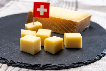 schweizer gruyere und wein Gruyère-Käsewürfel auf Schieferplatte