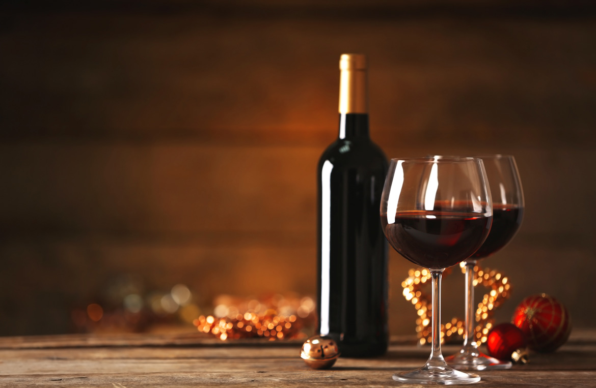 Rotweinflasche und Rotweinglas auf geschmückten Tisch zum Fest