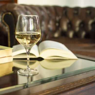 Weinglas mit Weißwein vor aufgeschlagenem Buch