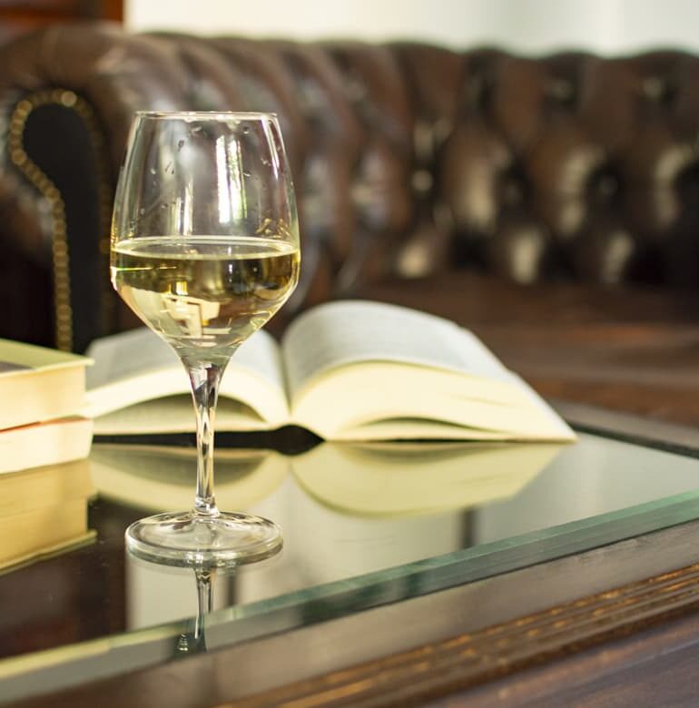 Weinglas mit Weißwein vor aufgeschlagenem Buch