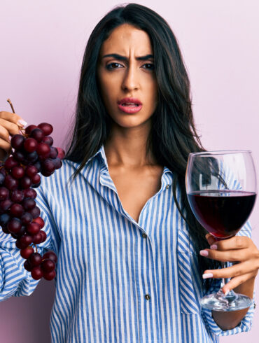 Frau mit Weintrauben und Rotweinglas in den Händen