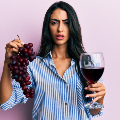 Frau mit Weintrauben und Rotweinglas in den Händen