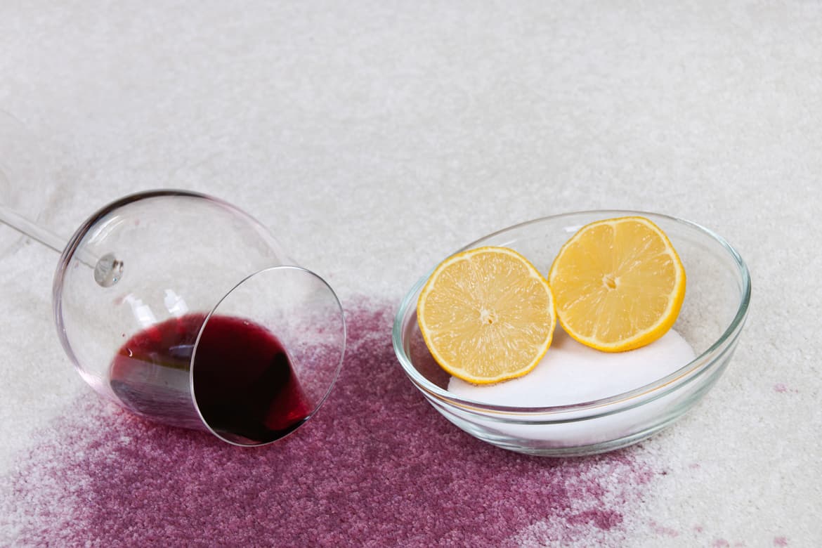 Rotweinfleck auf Teppich und Schüssel mit Salz und Zitrone