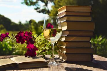 Weißweinglas vor Büchern mit Weinsprache