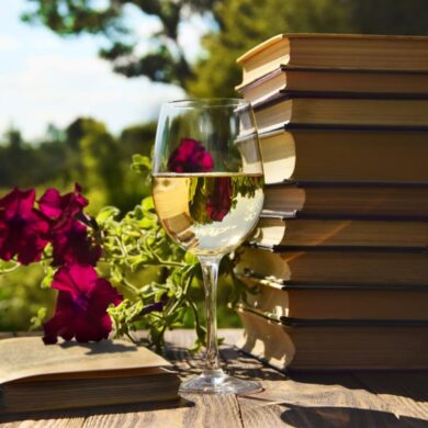 Weißweinglas vor Büchern mit Weinsprache