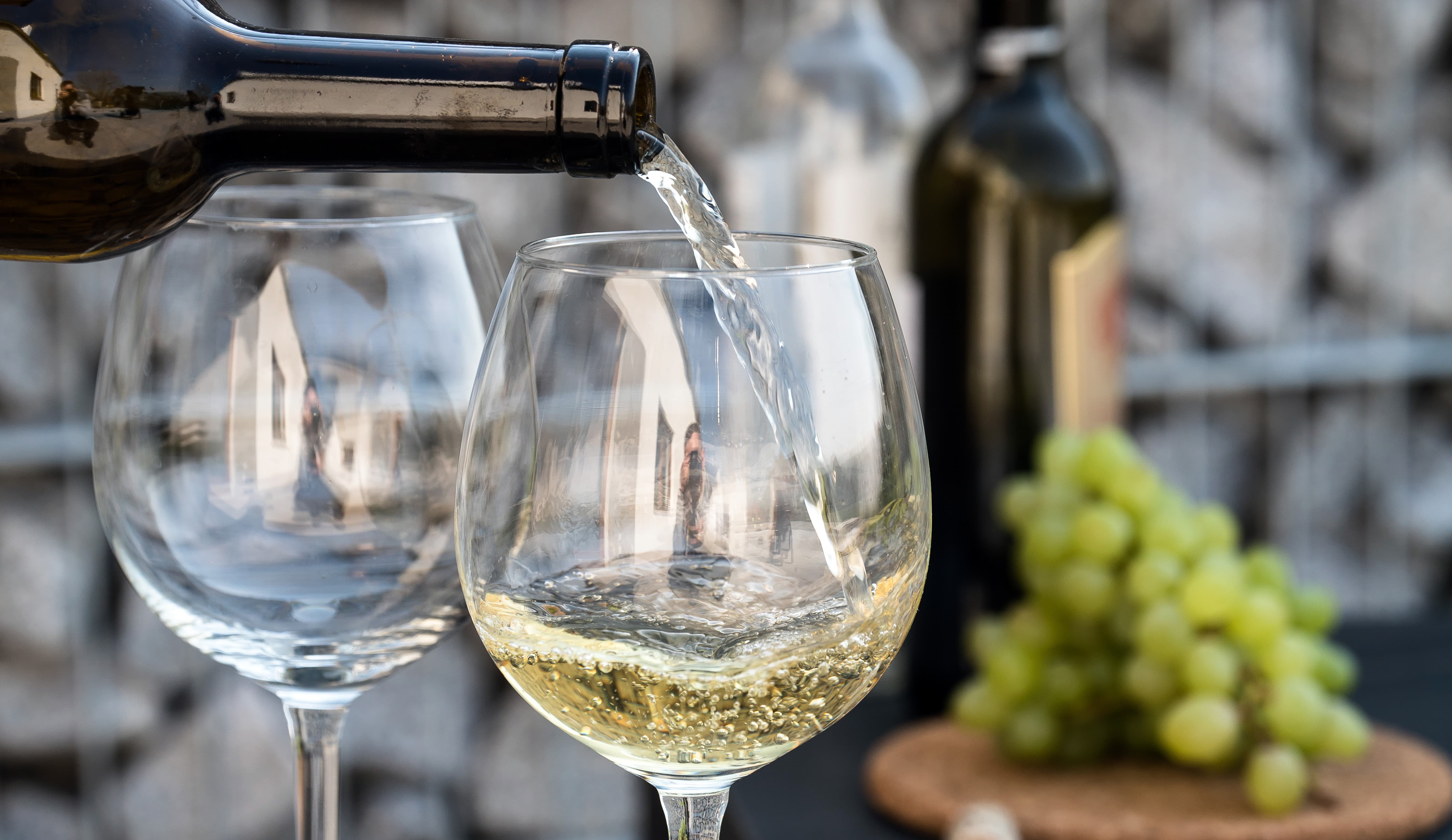 Zwei Weingläser werden mit Weißwein gefüllt