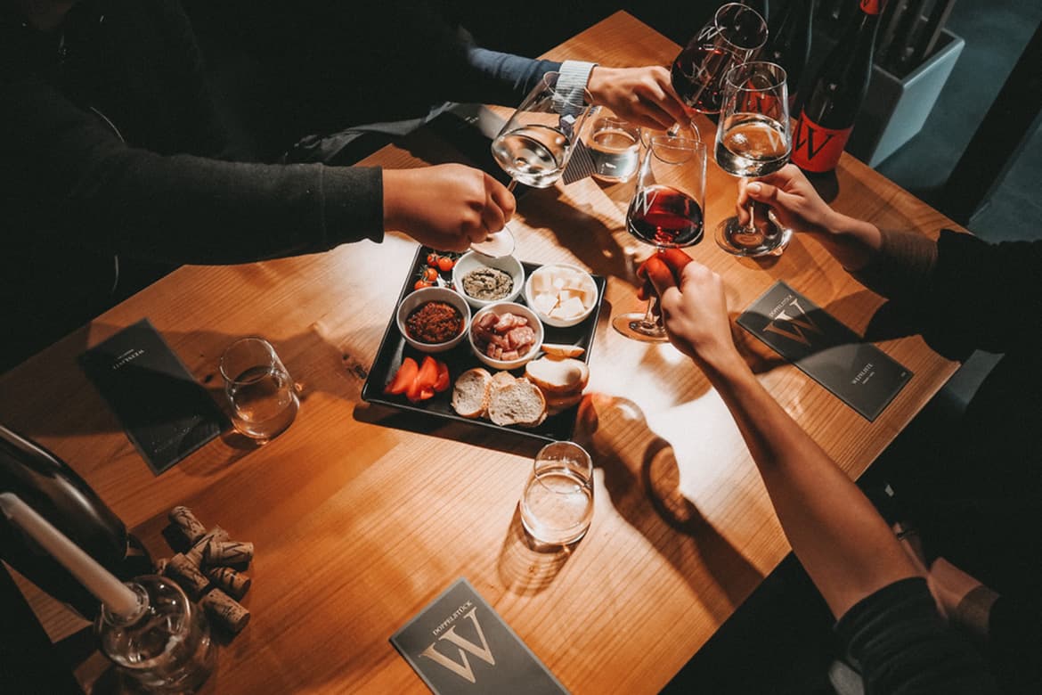 Menschen um einen Tisch mit Wein und Essen