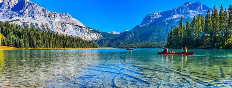 See in kanadischer Berglandschaft mit Leuten, die Kanu fahren