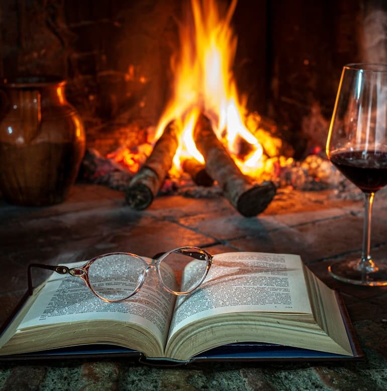 Buch und Rotweinglas für Kaminfeuer