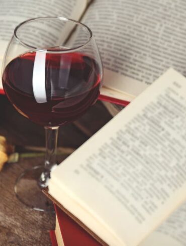 Buch und Glas Rotwein auf Tisch
