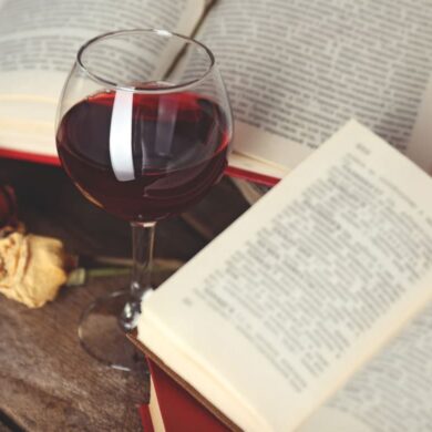 Buch und Glas Rotwein auf Tisch