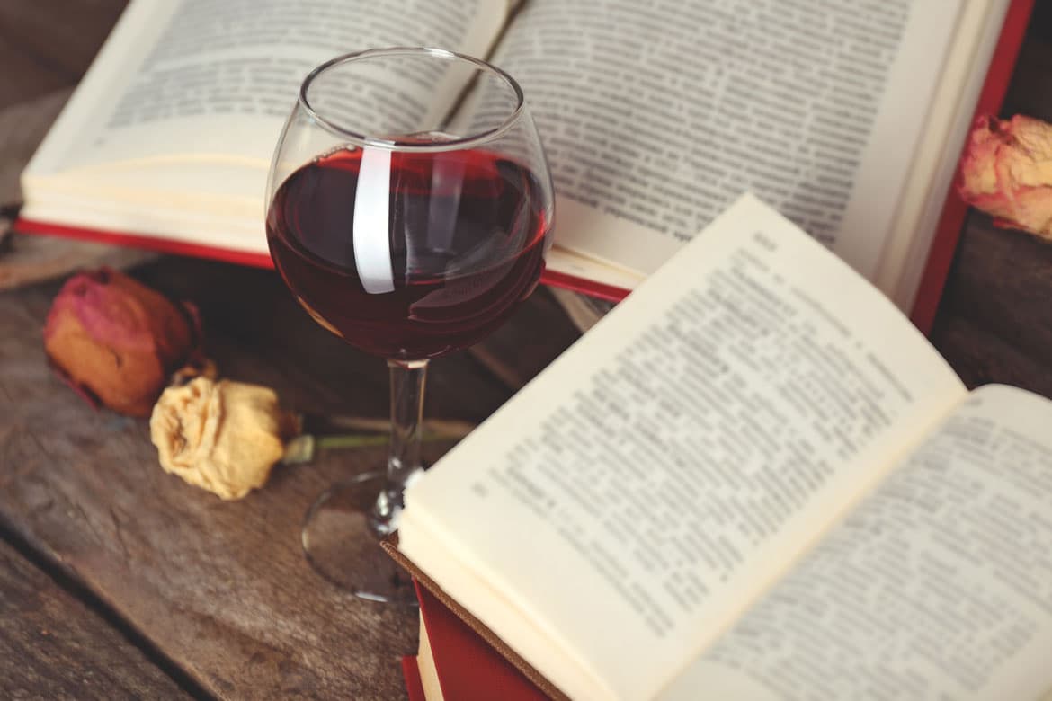 Buch und Glas Rotwein auf Tisch